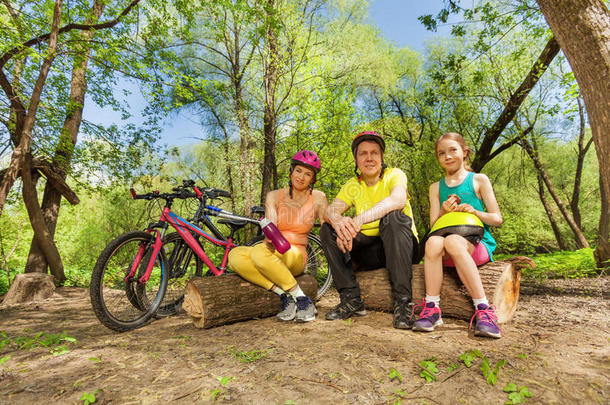 骑自行车后，活跃的家庭休息在原木上