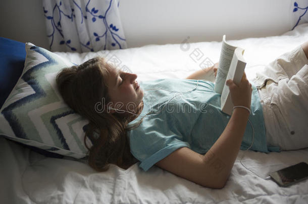 女孩躺在床上看书。