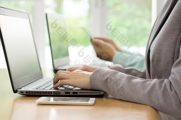 一个年轻的女人在办公室工作，坐在桌子上，用笔记本电脑