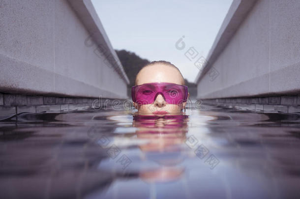 在无限屋顶游泳池里，戴紫色太阳镜的女人的脸特写