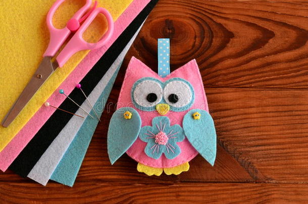 可爱的粉红色和蓝色猫头鹰玩具，彩色毡<strong>床单</strong>，木桌上的剪刀。 织物猫头鹰点缀