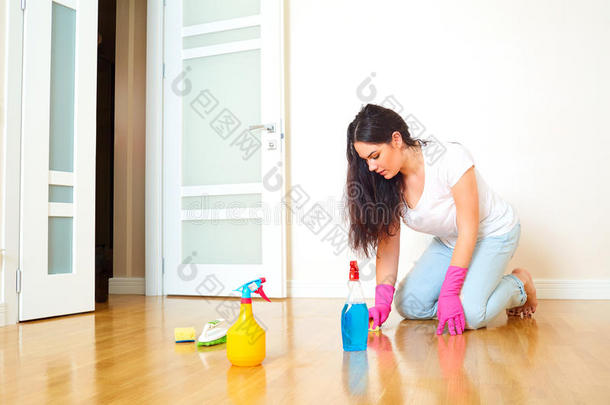 房子里的一个女人戴着橡胶手套打扫地板。 妈妈打扫公寓。 概念