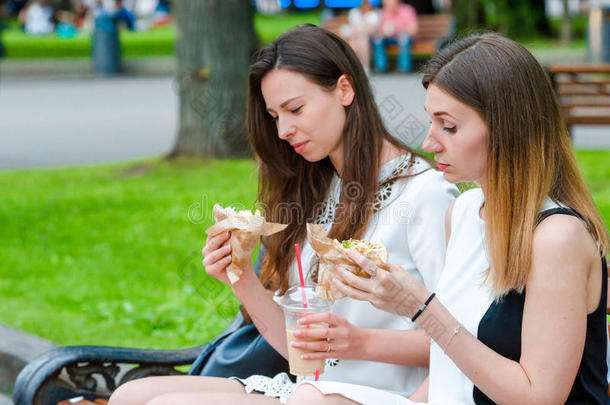 高加索妇女在户外街头吃汉堡包快餐三明治。 活跃的女孩饥饿，吃街头食物