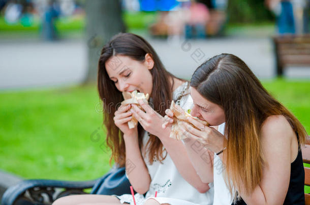 高加索妇女在户外街头吃汉堡包快餐三明治。 活跃的女孩饥饿，吃街头食物