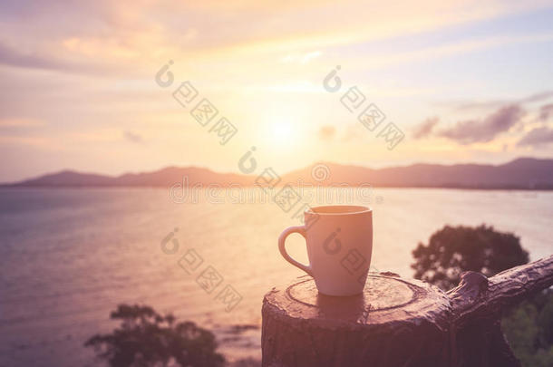 咖啡杯在日落或日出海滩与镜头耀斑。 瓦
