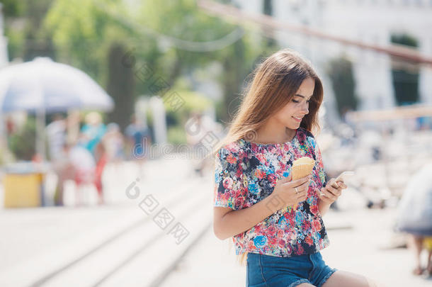 带冰淇淋的漂亮女孩在手机上读留言