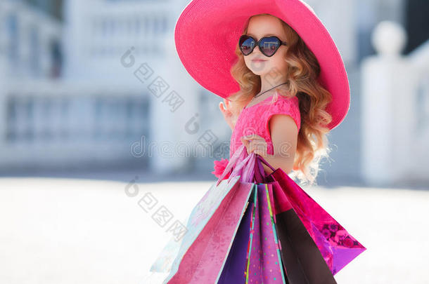 可爱的小女孩戴着时尚帽子，购物袋在超市旁边