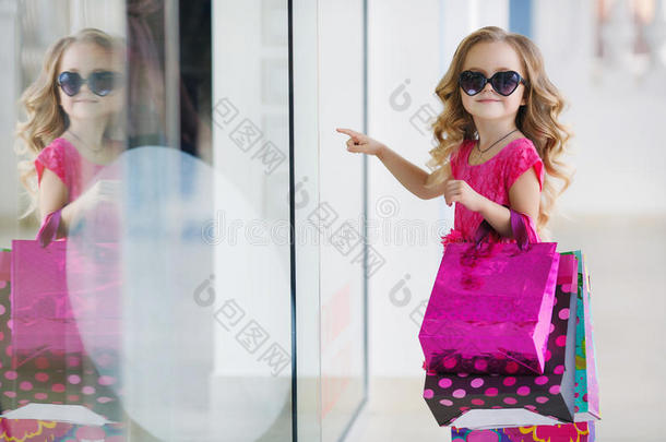 可爱的小女孩带着五颜六色的袋子在超市购物