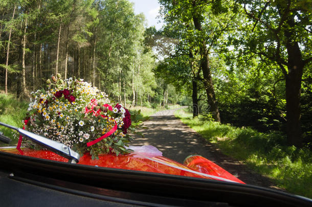 一束玫瑰，雏菊和其他野花作为婚礼装饰在一辆红色的老式汽车上