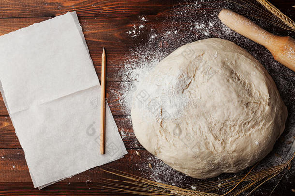 面团与面粉，烤纸，擀面杖，小麦耳朵在乡村桌面视图。 面包或比萨饼的自制糕点。