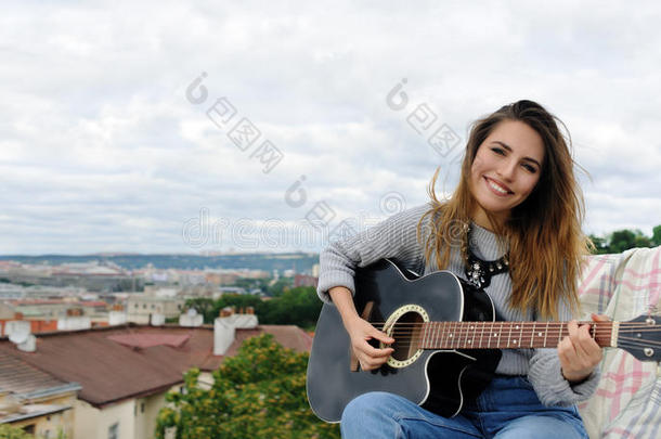 女孩在公园的背景上弹吉他