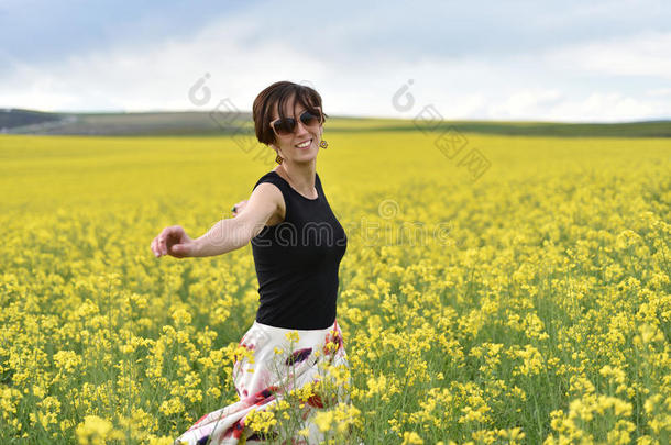 美丽的女人在油菜籽地里欢呼，享受夏天