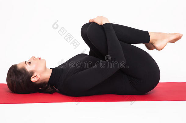 穿着黑色西装的漂亮运动女孩在做瑜伽。阿帕纳萨纳阿帕纳姿势。隔离在白色背景上。