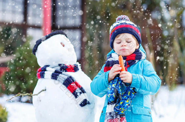 有趣的男孩在冬天的户外堆雪人