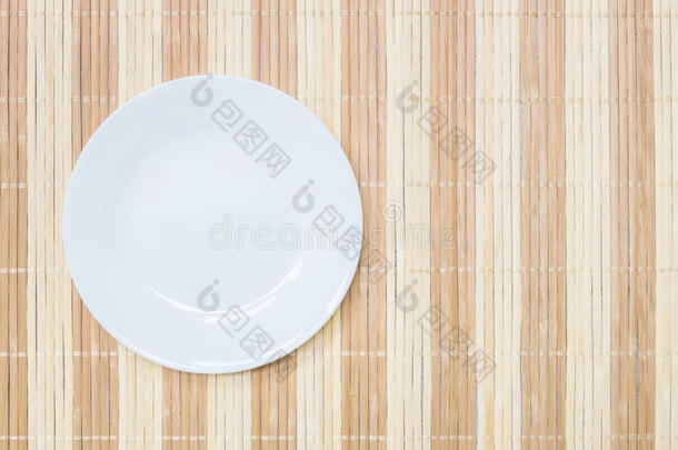 特写白色陶瓷盘子在木<strong>垫</strong>纹理<strong>背景</strong>在餐<strong>桌</strong>上的顶部视图与复制空间