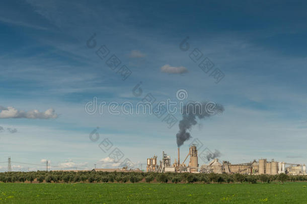 绿色的田野和工厂，黑烟从烟囱里冒出来