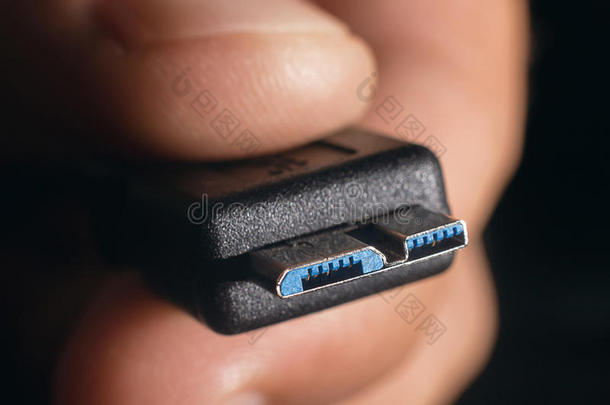 手握黑色微型USB3.0电缆。 男人的手拿着USB连接器。 特写男子手拿USB电缆。