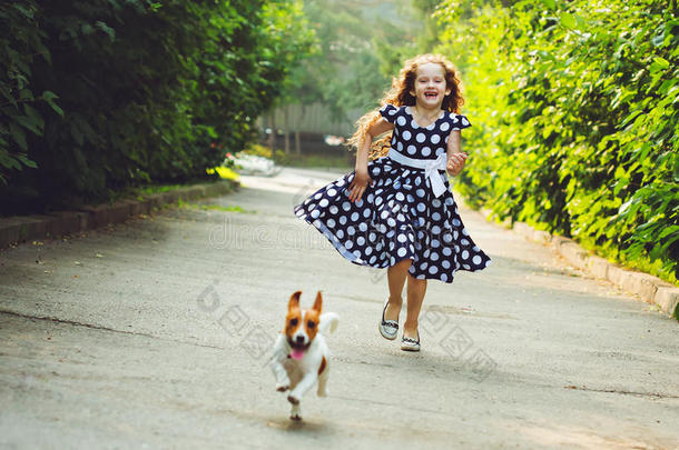 女孩和一只小狗杰克·罗素猎犬在公园里跑。