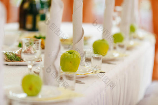 绿色的苹果站在餐厅桌子上的空盘子上