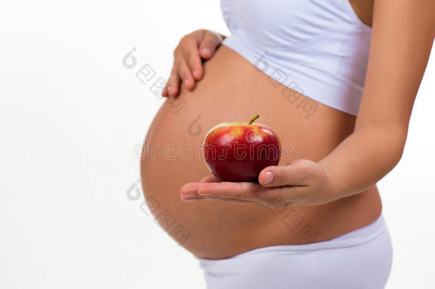 孕妇腹部和苹果的特写。 怀孕期间的维生素和健康食品