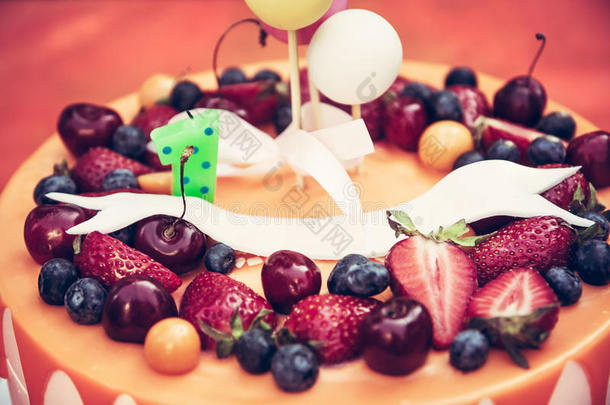 <strong>儿童生日</strong>蛋糕与浆果和滴橙色釉在橙色背景