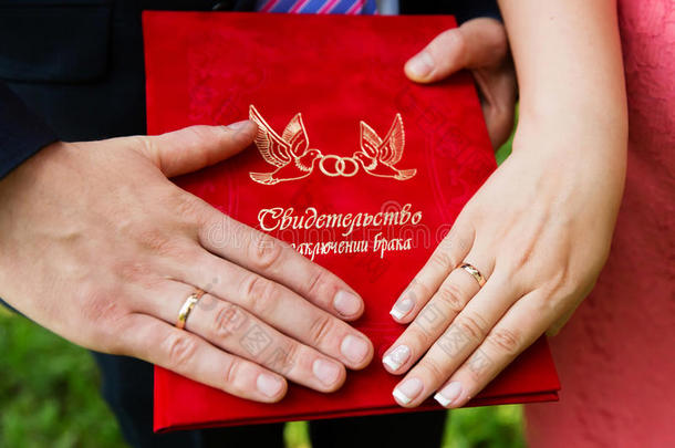 结婚证书上有结婚戒指的手。