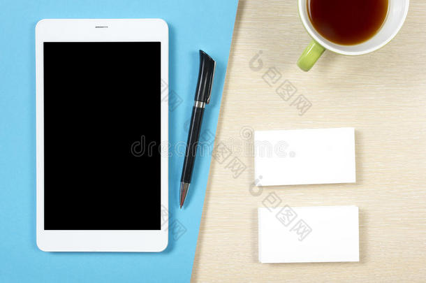 名片空白，智能手机或平板电脑，咖啡杯和钢笔在办公桌桌面视图。 公司文具