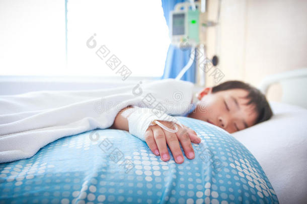 亚洲男孩躺在病床上用生理盐水静脉注射(Iv)。 健康