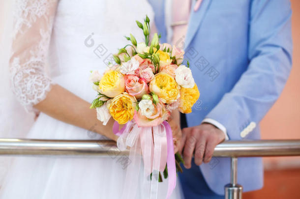 新娘和新郎拿着五颜六色的婚礼花束。 婚姻观念