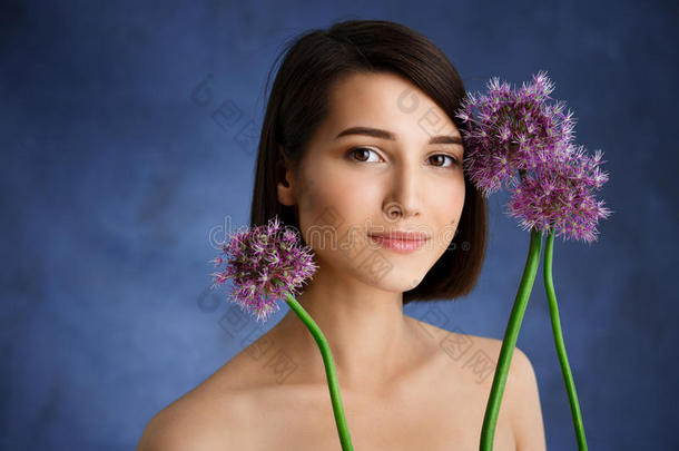 特写蓝色背景上淡紫色花朵的温柔年轻女孩的肖像