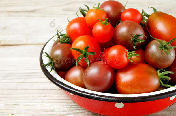 新鲜的红色和黑色<strong>樱桃</strong>西红柿在<strong>一个</strong>金属碗在<strong>一个</strong>木制的背景。