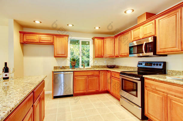 明亮的厨房房间，配有浅棕色橱柜和钢制电器