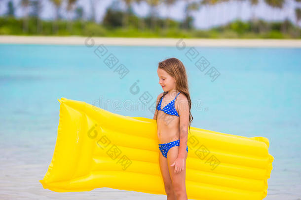 可爱的小女孩在海滩度假时带着充气床垫