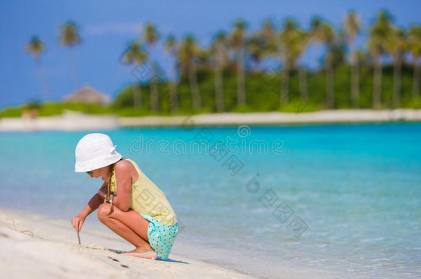 暑假里海滩上可爱的小女孩在沙滩上画画