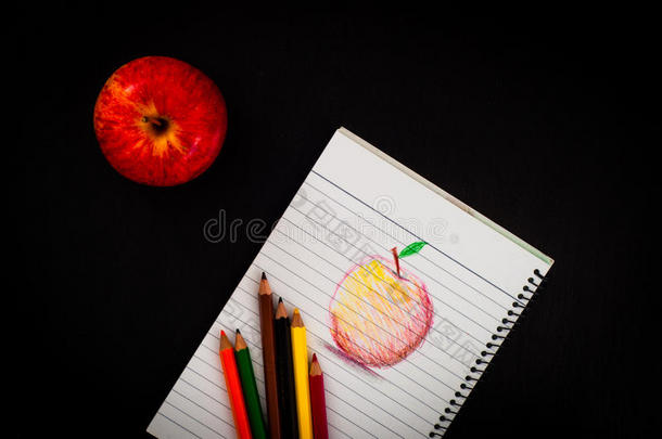 几支彩色铅笔在<strong>素描</strong>簿上用手画艺术红苹果<strong>素描</strong>，在深色木桌面上用读苹果的内衬纸上画