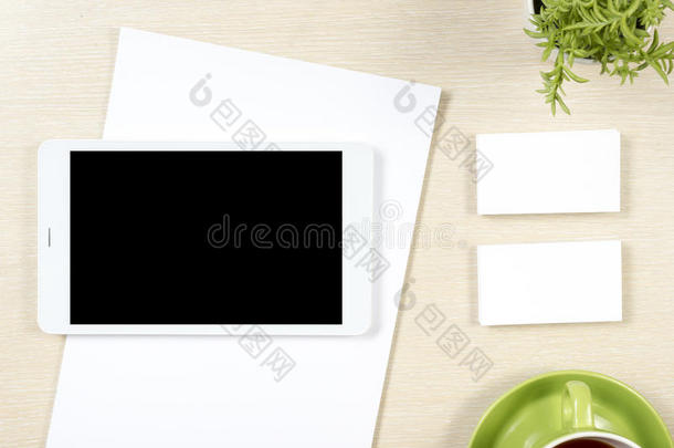 名片空白，智能手机或平板电脑，花和咖啡杯在办公桌桌面视图。 公司文具