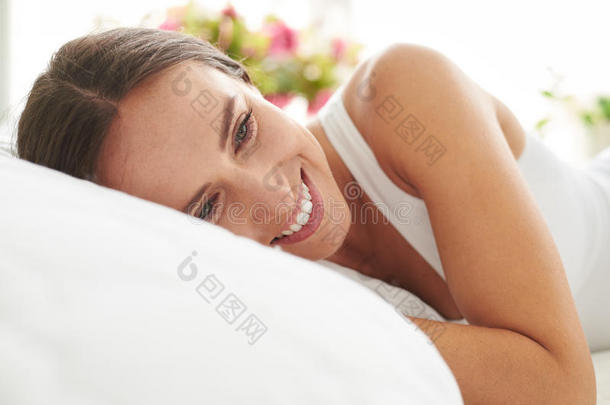 快乐微笑的年轻女人在床上放松
