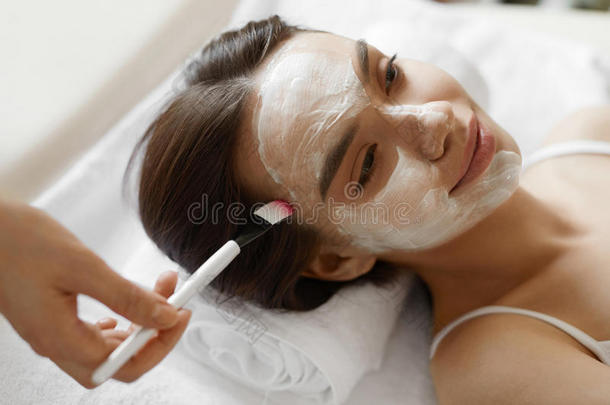 面部美容治疗。 美丽的女人得到化妆品面具