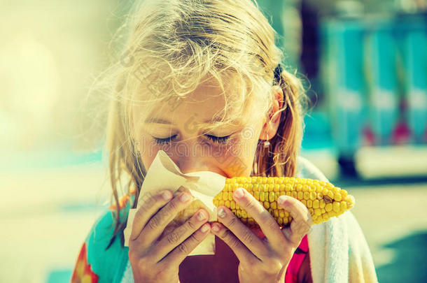 可爱的小女孩吃甜玉米。色调照片
