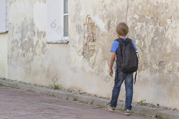 背着背包走在街上的男孩。后视图。人文教育、学校、旅游、休闲理念