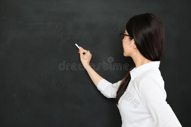 一个好的亚洲老师用粉笔在黑板上写字