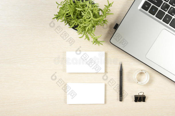 名片空白，笔记本电脑，花和铅笔在办公桌桌面视图。 企业文具品牌模型
