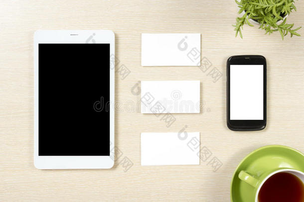 名片空白，智能手机或平板电脑，花和咖啡杯在办公桌桌面视图。 公司文具