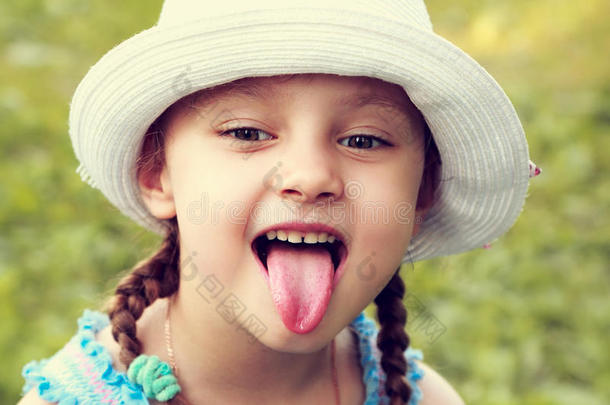 有趣的女孩戴着时尚帽子，用幽默的脸露出舌头