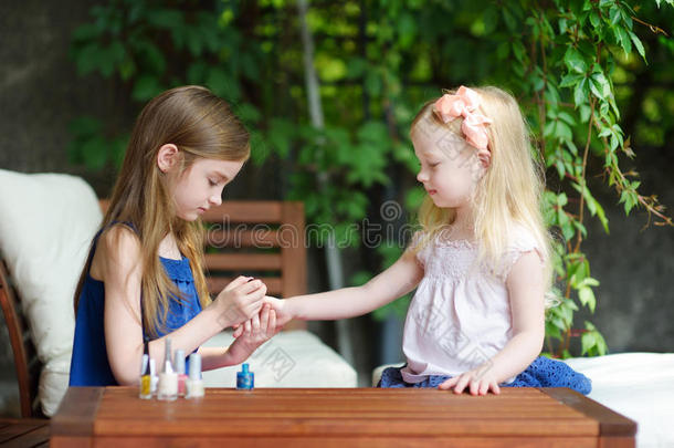 可爱的小女孩在家里玩得很开心，用五颜六色的指甲油做指甲和涂指甲