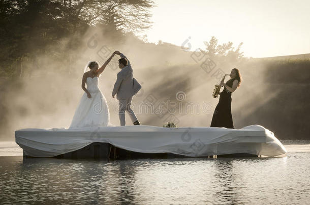 新娘和新郎在湖边跳舞听音乐。