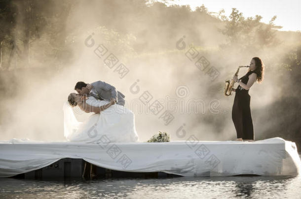 新娘和新郎在湖边跳舞听音乐。