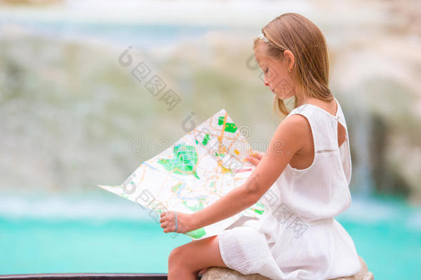 可爱的小女孩看旅游地图附近的特雷维喷泉，罗马，意大利。 快乐的托德勒孩子喜欢意大利假期