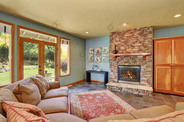 舒适的客厅，蓝色的墙壁和石头瓷砖壁炉。