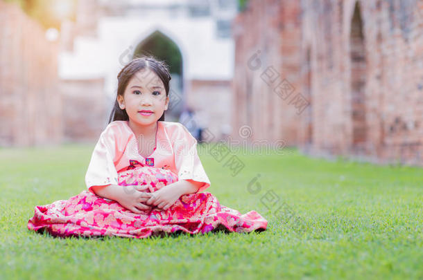 穿着韩国服装的可爱女孩坐在草地上